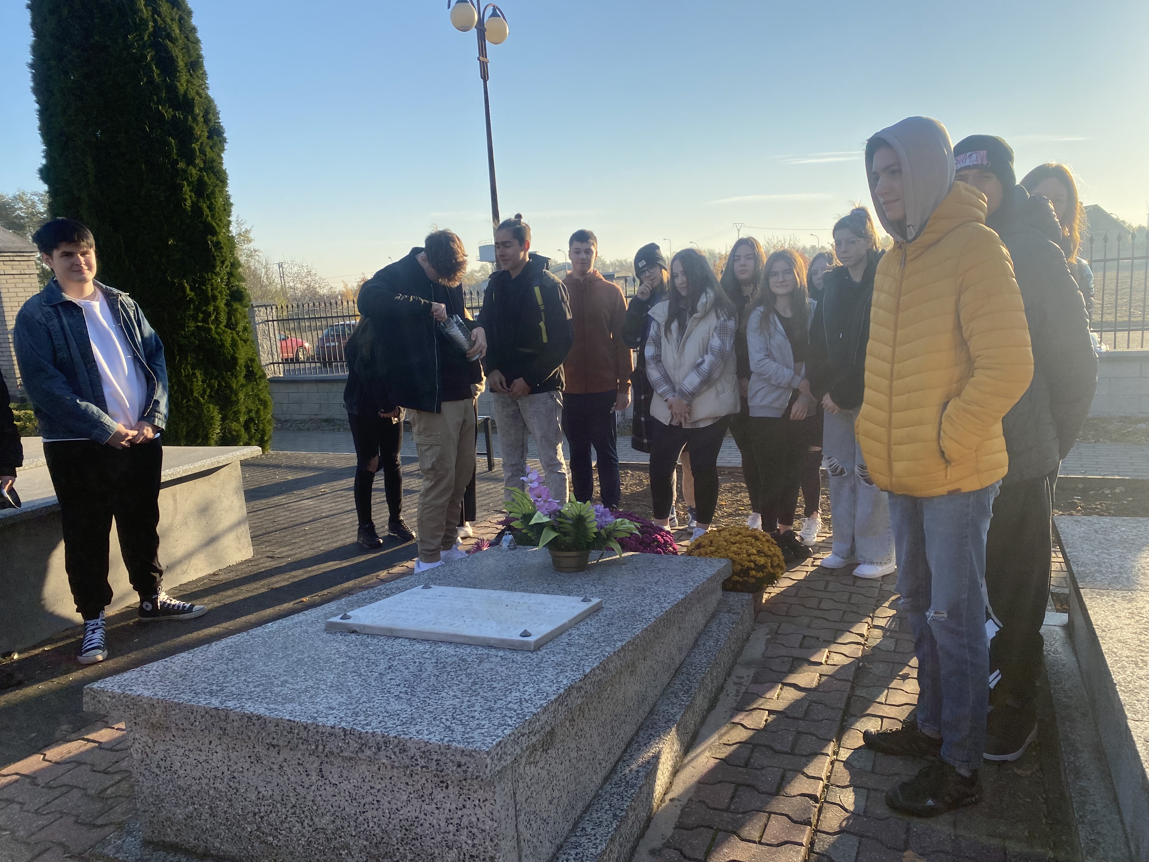 Osoby stoją przy pomniku