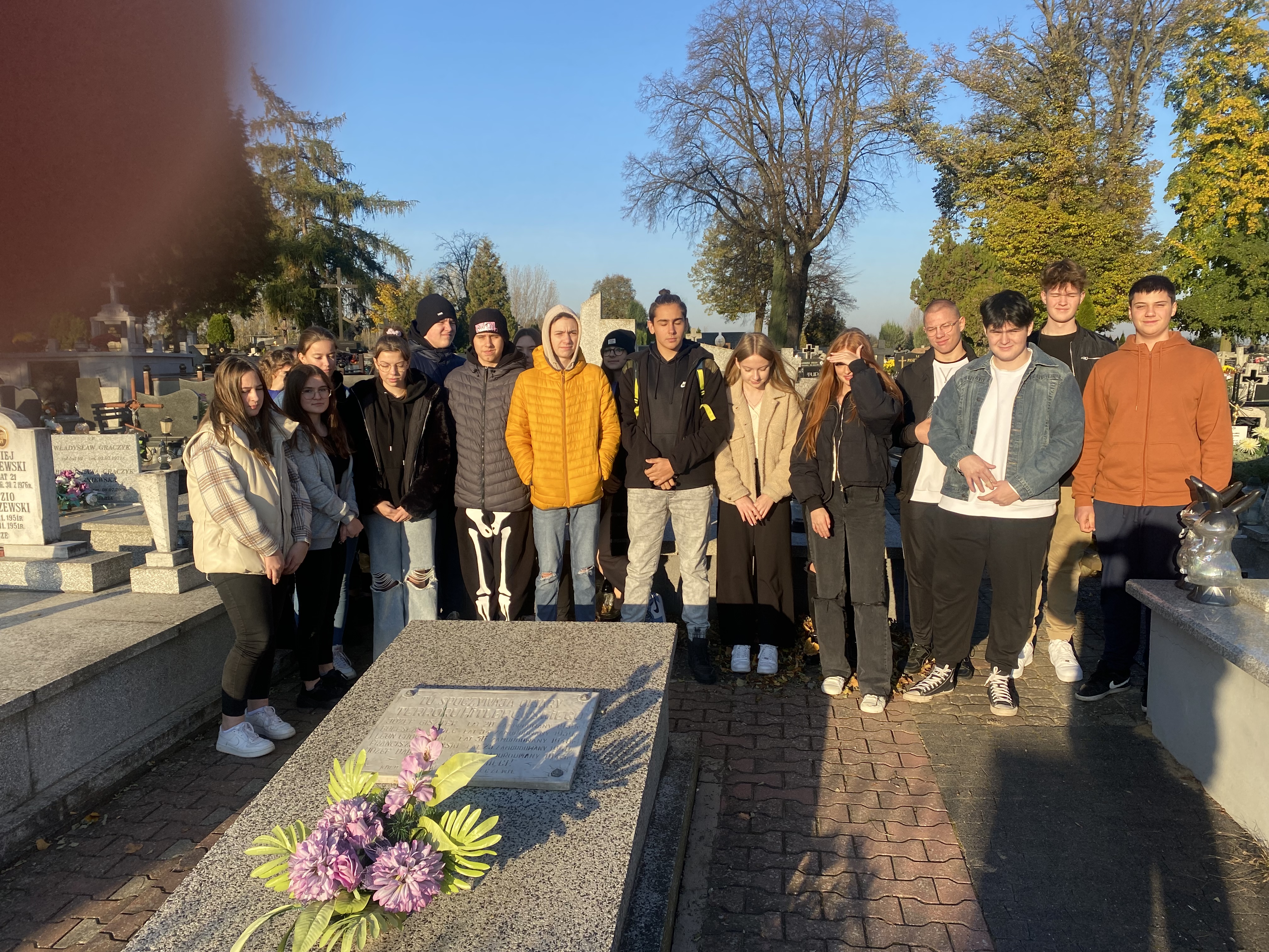 Osoby stoją przy pomniku